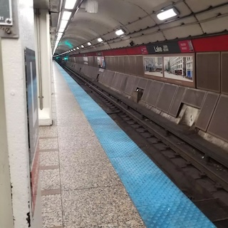 Photograph of a subway station, looking off the platform and down one of the tunnels. 